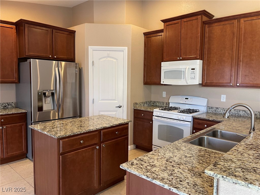 92 Whitetail Archery Avenue North Las Vegas, NV 89084 - Photo 10 of 33 Kitchen featuring white appliances, light stone countertops, light tile patterned floors, and a center island