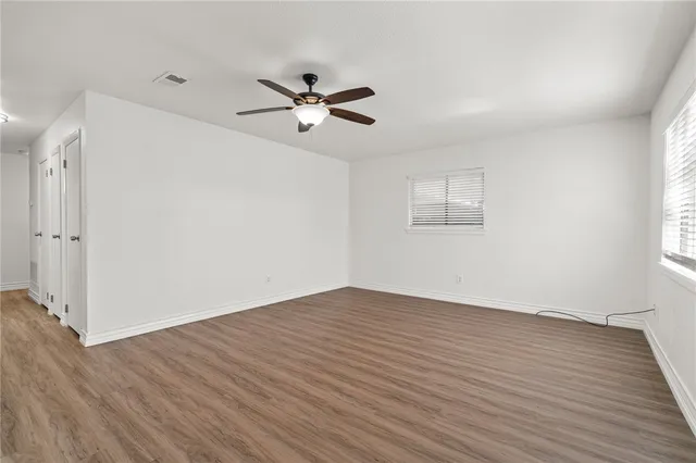 a view of empty room with wooden floor and fan