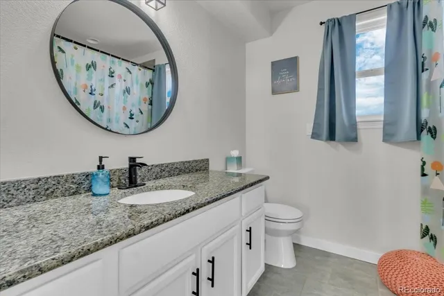 a bathroom with a granite countertop toilet a sink and a mirror