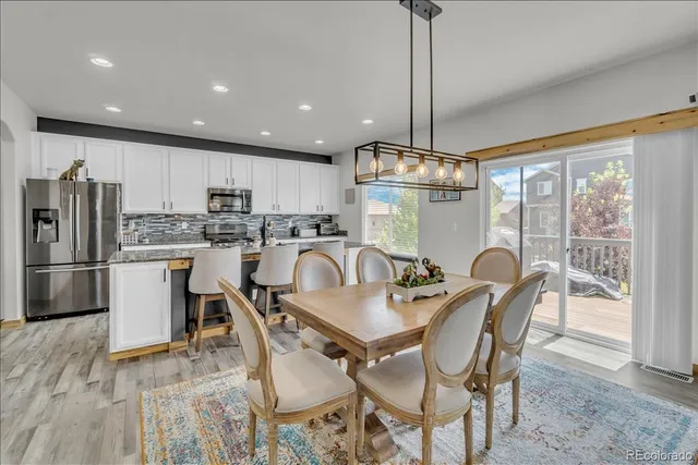 a dining room with stainless steel appliances furniture a chandelier and kitchen view