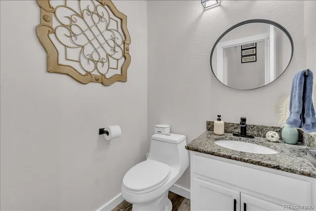 a bathroom with a granite countertop toilet sink mirror and vanity