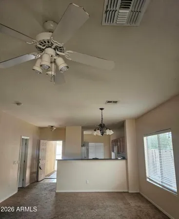 a view of an empty room and chandelier fan