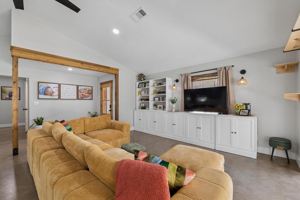 286 Benevolence Way China Spring, TX 76633 - Photo 6 of 37 Spacious living area featuring high vaulted ceilings, recessed lighting, concrete flooring, and a built-in entertainment center with open shelving and cabinet storage