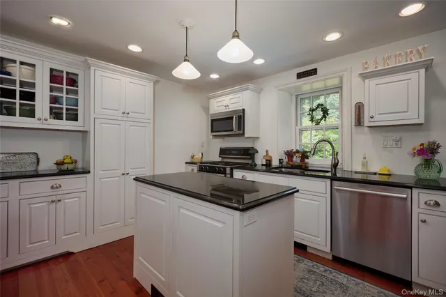 a kitchen with stainless steel appliances granite countertop a sink a stove and a wooden floors