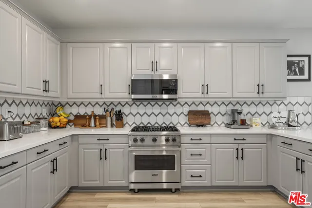 a kitchen with white cabinets and appliances