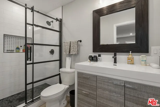 a bathroom with a toilet sink vanity granite and shower