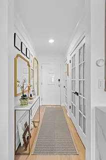 a view of a hallway to a livingroom with wooden floor and furniture