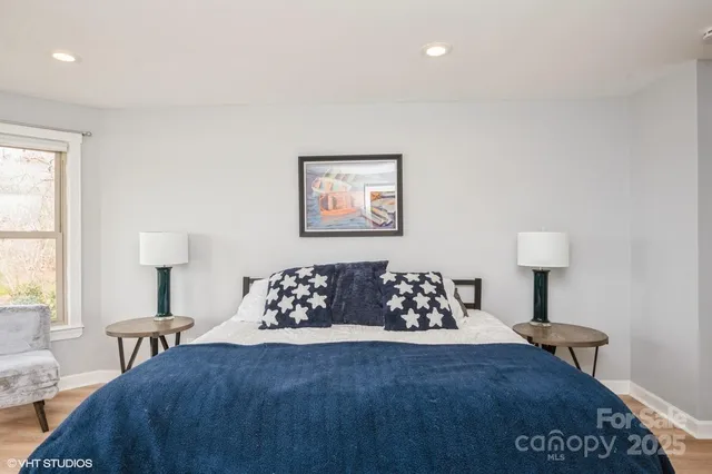 a bed sitting in a bedroom next to a window with a lamp and a small yard