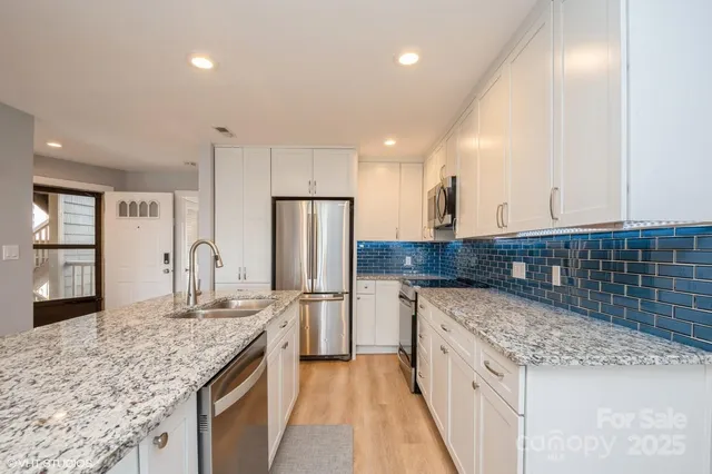 a kitchen with stainless steel appliances granite countertop a sink and a refrigerator