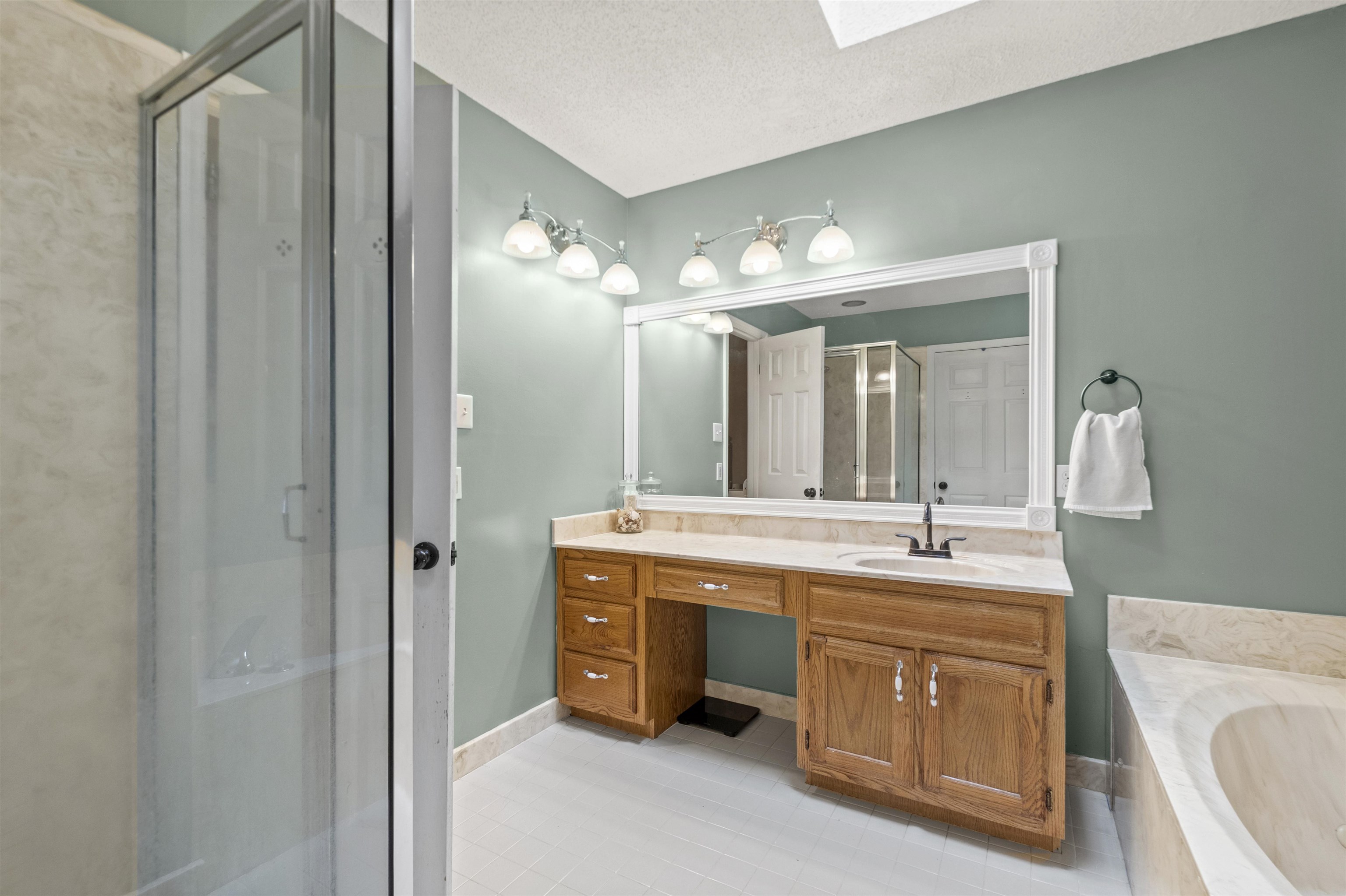 3601 Marshall Road Munford, TN 38058 - Photo 30 of 35 Bathroom featuring a glass-enclosed shower, a built-in vanity with a single sink, a large mirror, a four-light fixture, and a built-in bathtub with stone surround