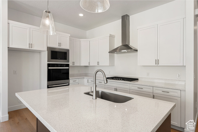 549 North Legend Circle, Unit C/466 Mapleton, UT 84664 - Photo 16 of 39 Kitchen featuring wall chimney range hood, stainless steel appliances, wood finished floors, white cabinetry, and light stone counters