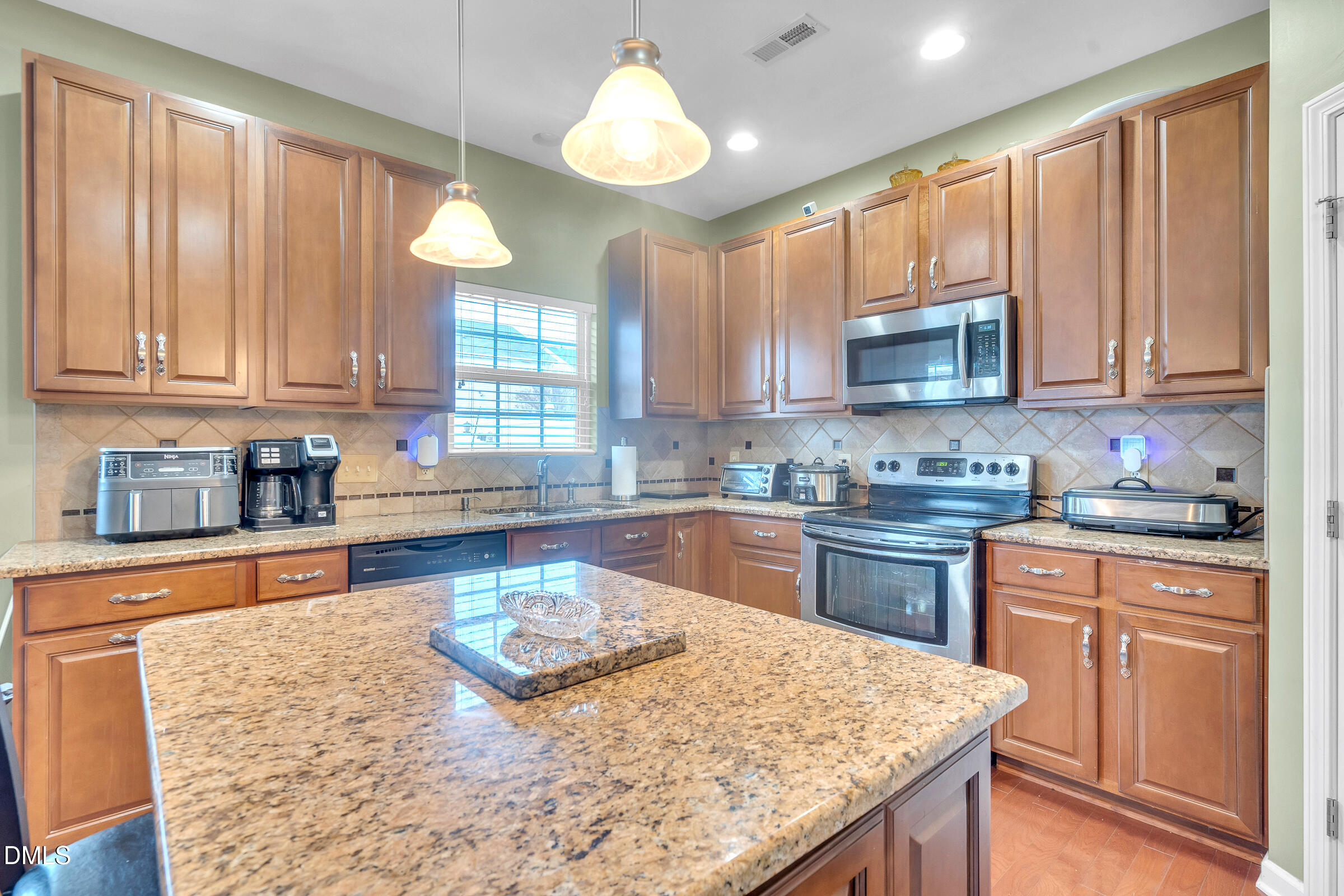 5165 Busted Rock Trail Raleigh, NC 27610 - Photo 8 of 18 a kitchen with kitchen island granite countertop wooden cabinets a stove a sink a window and stainless steel appliances