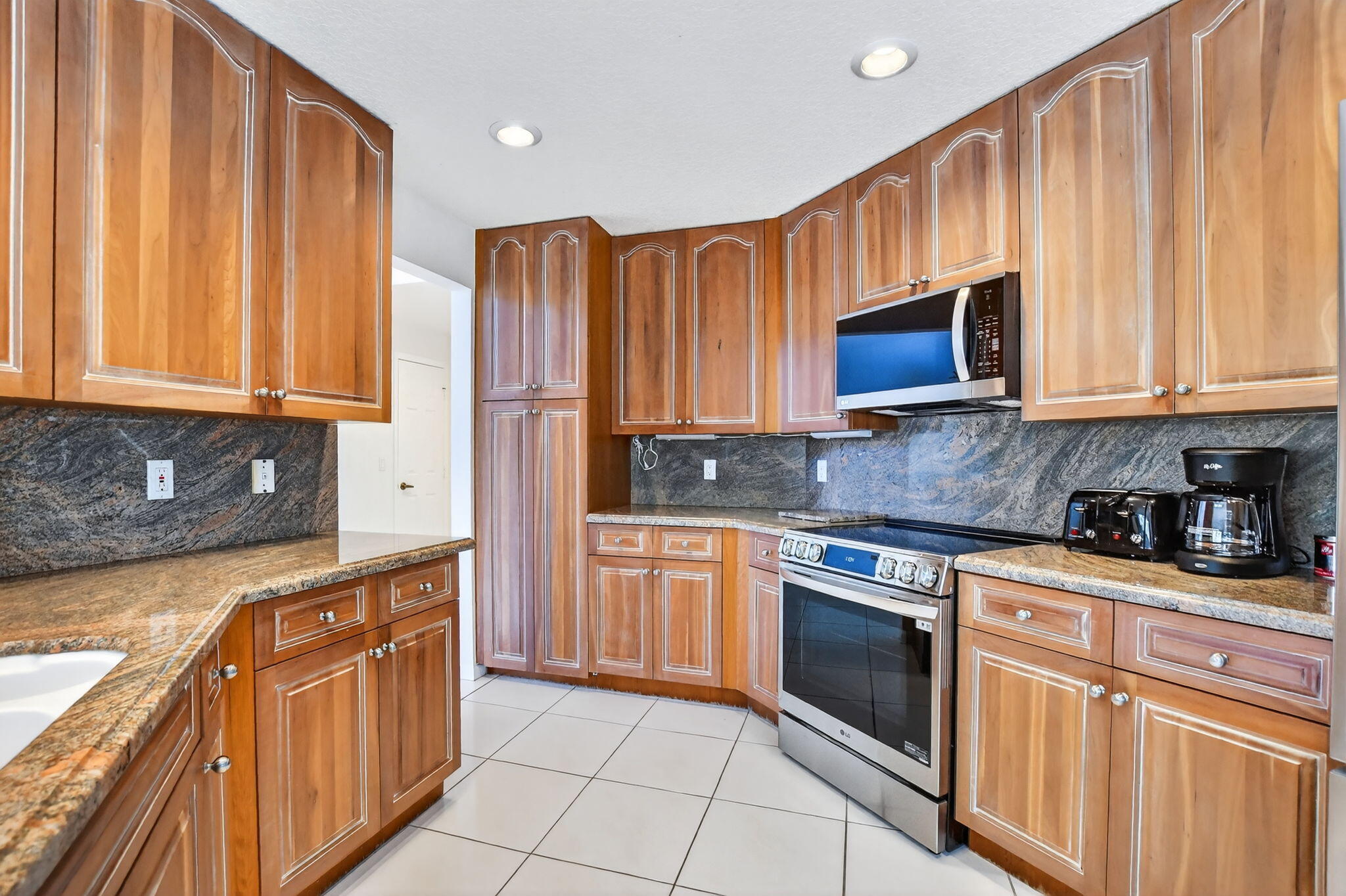 23429 Rakelle Circle Boca Raton, FL 33433 - Photo 7 of 75 a kitchen with stainless steel appliances granite countertop a stove a sink dishwasher and a microwave oven with cabinets