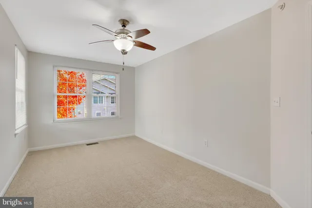 a view of empty room with wooden floor and ceiling fan