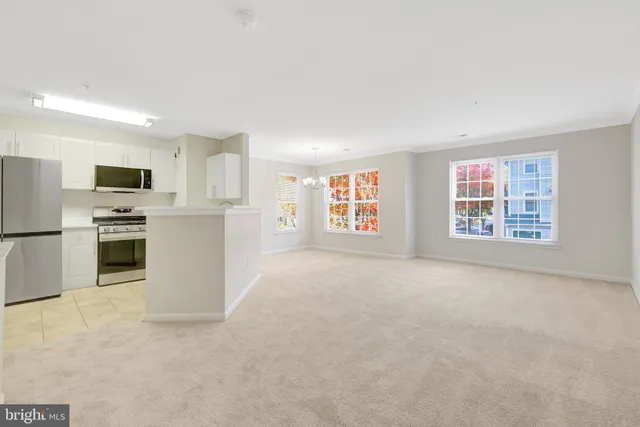 a view of kitchen with microwave oven a refrigerator and cabinets