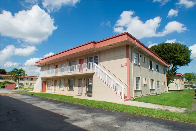 a front view of a house with a garden and trees