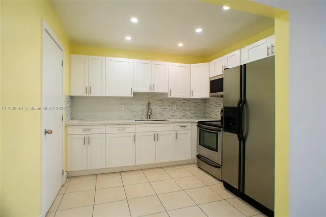 a kitchen with a sink a refrigerator and cabinets