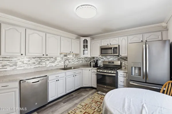 a kitchen with granite countertop a sink stainless steel appliances and white cabinets