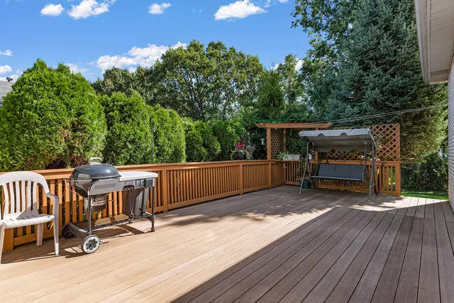 a view of house with deck outdoor seating and covered with trees