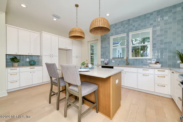 a open kitchen with stainless steel appliances granite countertop a sink a stove a dining table and chairs with wooden floor