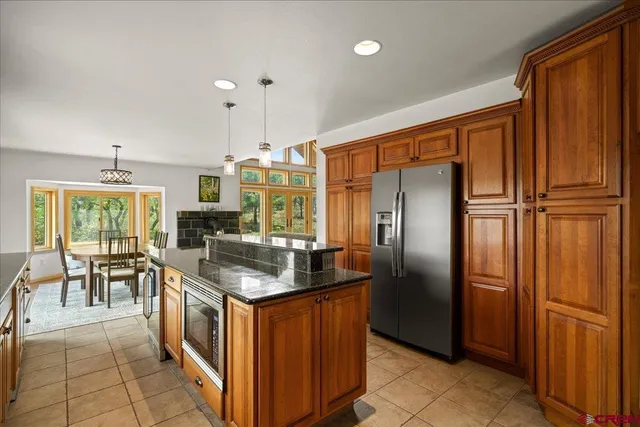 a kitchen with stainless steel appliances granite countertop a refrigerator a stove a sink and a dining table