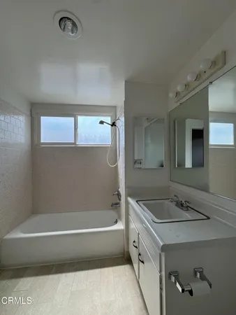 a bathroom with a tub a sink and mirror