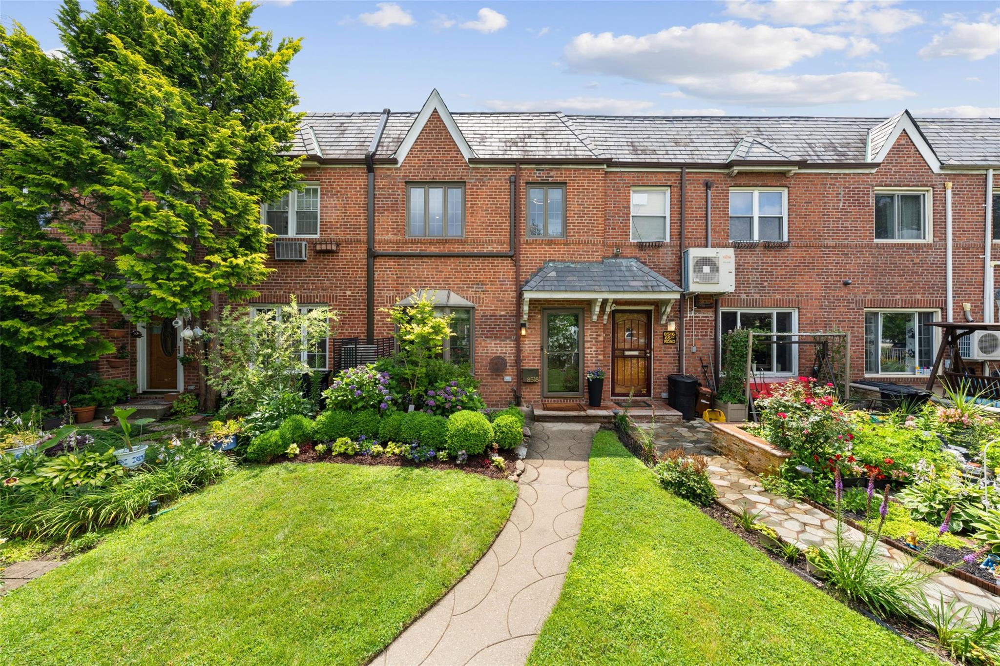 View of front of house with a front yard, brick siding, and a high end roof