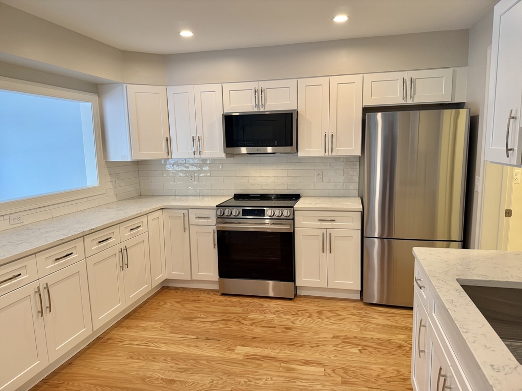 22 Barracks Road, Unit 22 Hudson, MA 01749 - Photo 3 of 15 a kitchen with granite countertop a refrigerator stove and microwave