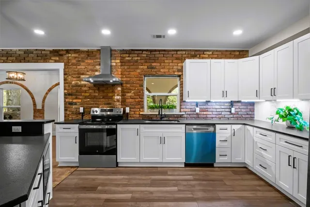 a kitchen with stainless steel appliances granite countertop a sink a stove and cabinets