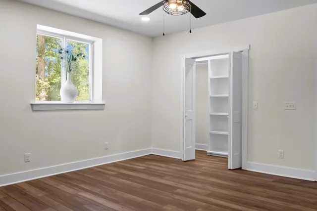 a view of an empty room with wooden floor and a window