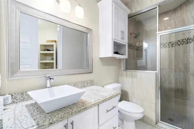 a bathroom with a granite countertop sink a mirror and a toilet