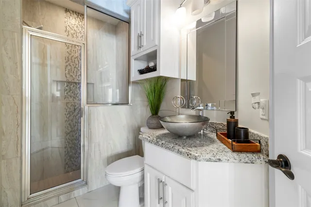 a bathroom with a granite countertop sink toilet and shower