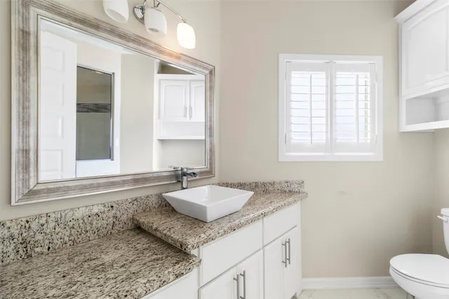 a bathroom with a granite countertop sink and mirror with window
