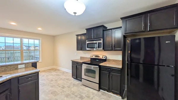 a kitchen with granite countertop stainless steel appliances a stove a sink and a refrigerator