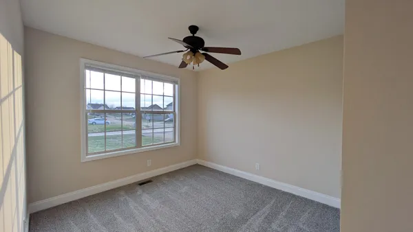 an empty room with windows and fan