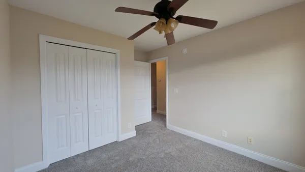 an empty room with a ceiling fan and a fan