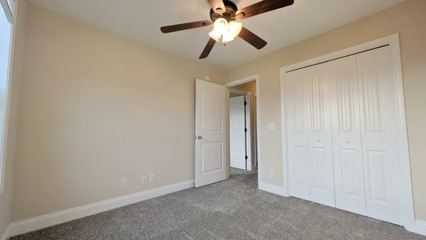 an empty room with closet and a chandelier fan