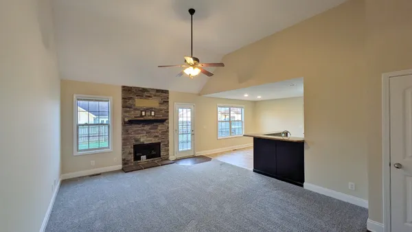 a view of a livingroom with a fireplace a chandelier and windows