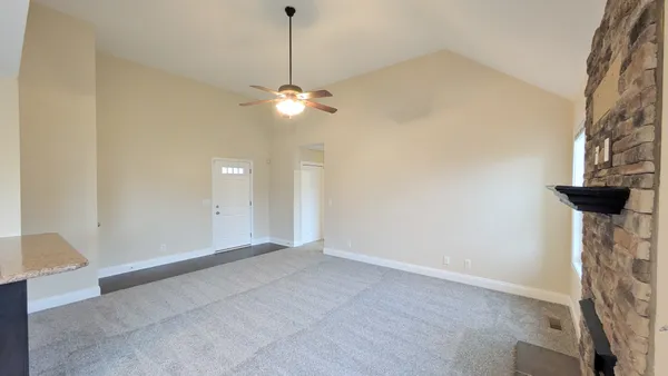 a view of an empty room with a chandelier fan