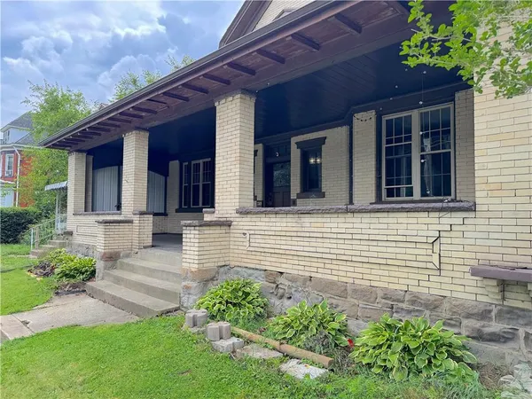 a view of a house with brick walls and a yard with plants