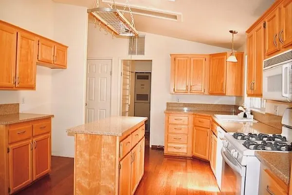 a kitchen with stainless steel appliances granite countertop a stove a sink and a refrigerator with wooden cabinets