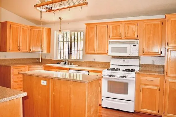 a kitchen with stainless steel appliances granite countertop a stove a sink and white cabinets with wooden floor