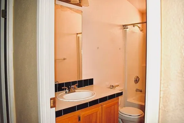 a bathroom with a granite countertop sink toilet mirror and shower