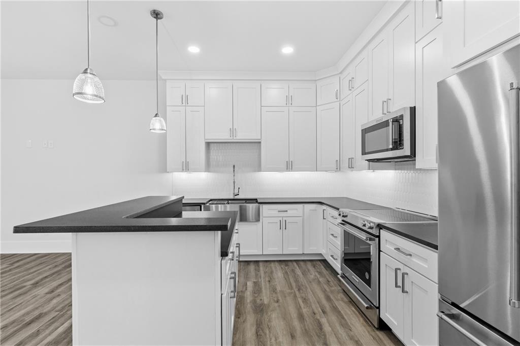 15448 Hopewell Road Milton, GA 30004 - Photo 74 of 125 a kitchen with stainless steel appliances granite countertop a sink a stove a refrigerator and island with wooden floor