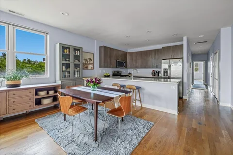 a living room with stainless steel appliances kitchen island granite countertop furniture wooden floor and a window