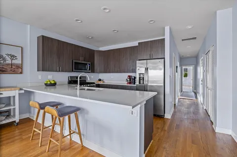 a kitchen with a refrigerator a sink a stove a microwave a dining table and chairs