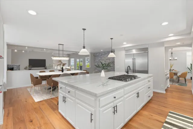 a kitchen with a stove a sink a refrigerator and chairs