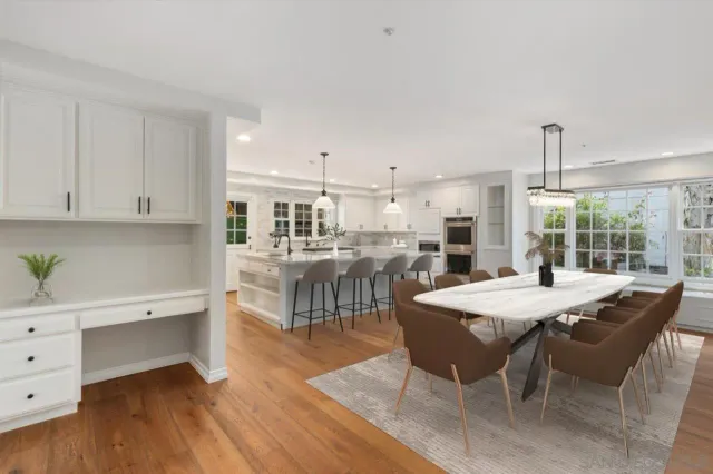 a room with stainless steel appliances kitchen island granite countertop a table chairs sink and cabinets