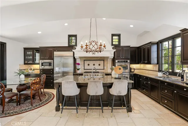 a view of a dining room with furniture a chandelier and kitchen view