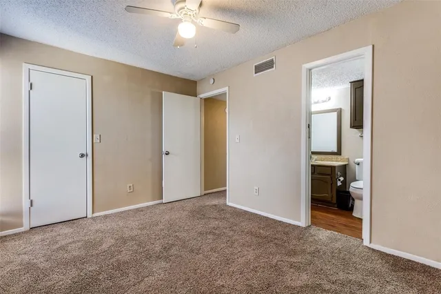 a view of an empty room with closet and a bathroom